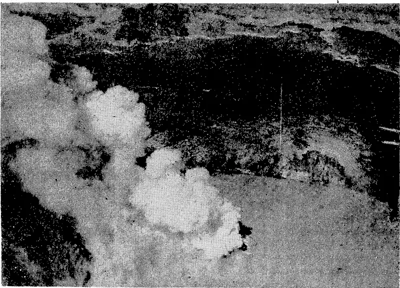 The crater lake on Mount Ruapehu, photographed yesterday, when the cone in the centre of the lake was erupting and sending up a column of steam and ashes. This photograph was taken from an aircraft by a Public Works Department photographer. (Evening Post, 22 March 1945)