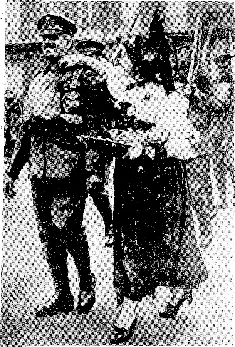 A French girl in Alsatian costume, selling poppies and cornflowers in the streets of Paris, attempts to put a floiver on the uniform of a British guardsman who has just arrived. (Evening Post, 09 December 1939)