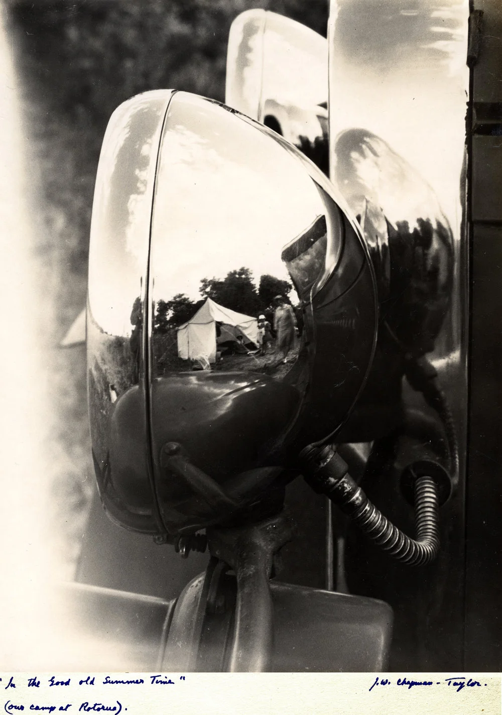 Camp tent reflected in chrome-plated car headlight housing.