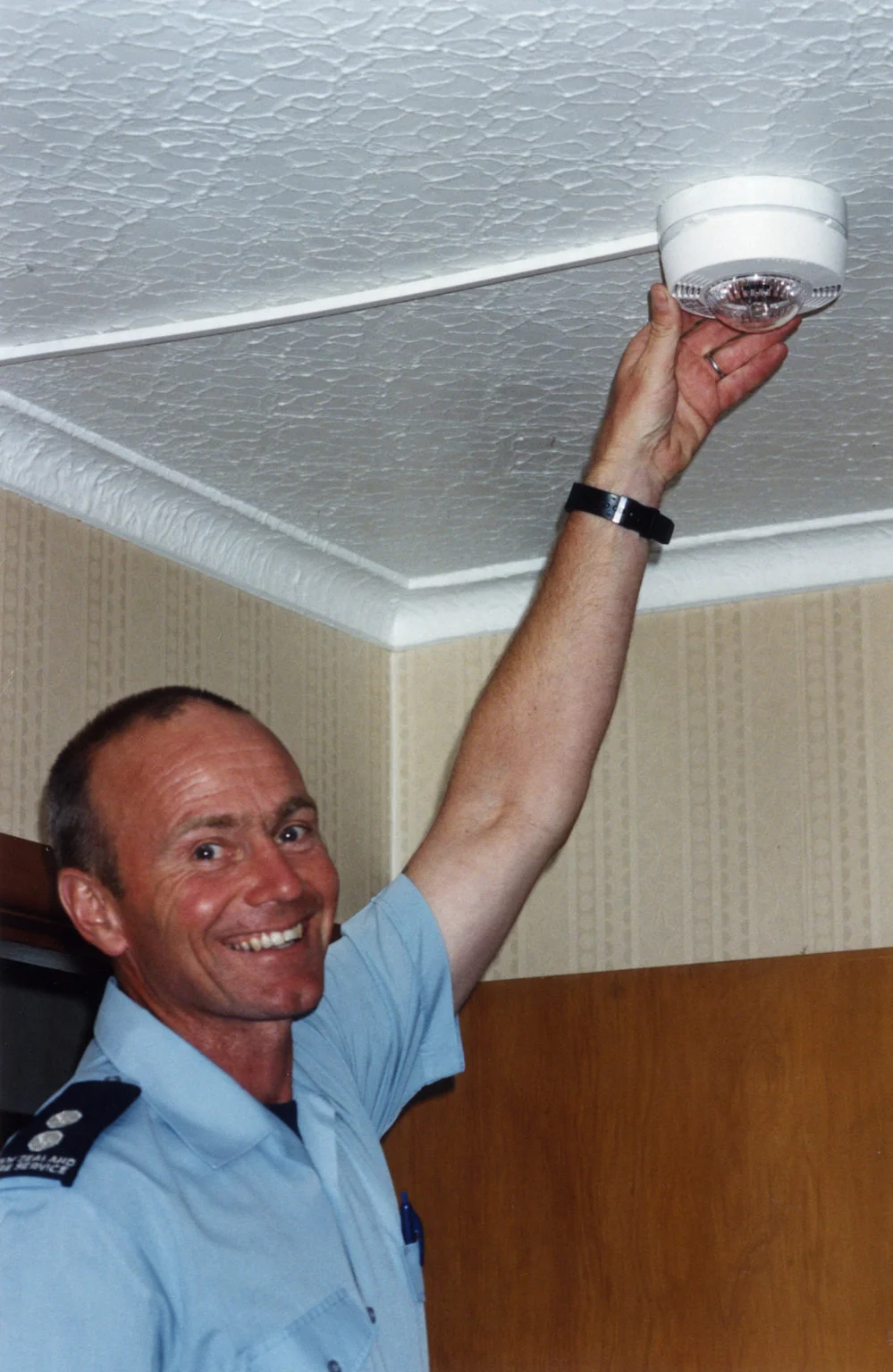 Fire safety; firefighter Jim Prescott with a smoke alarm for the hearing-impaired; strobe lights as well as sound.