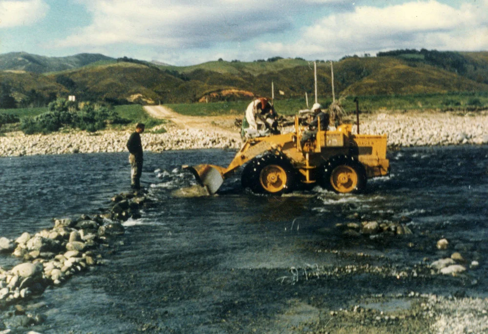 Totara Park bridge site; loader moving rocks in Te Awa Kairangi / Hutt River.