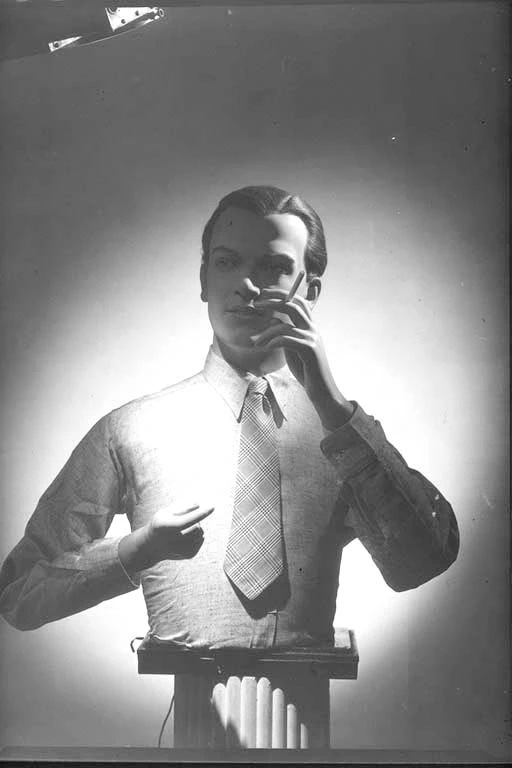 View of a mannequin on a stand in a shirt and tie smoking a cigarette