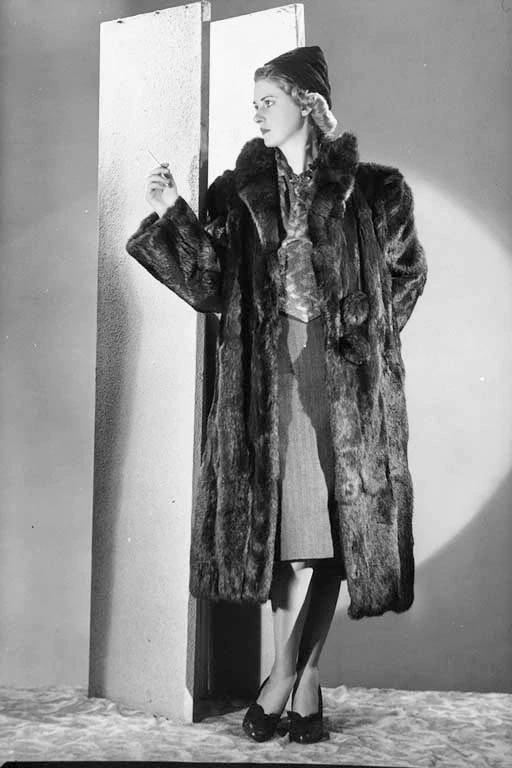 Full length portrait of a model wearing a full length fur coat and hat, for Mooney Furs