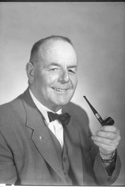 Head and shoulders portrait of Mr E L Thwaites smoking a pipe