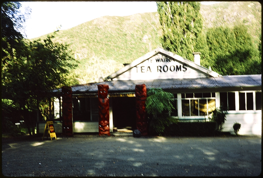 The Te Wairoa Tea Rooms with maori carvings below a Te Wairoa Buried Village sign at the entrance