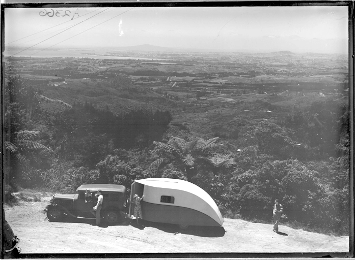 Showing an Aquires caravan parked by native bush in Titirangi? looking east with Auckland in the distance 1940?