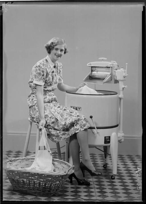 Full length model seated beside an "Easy" washing machine, for Bond and Bond 1940