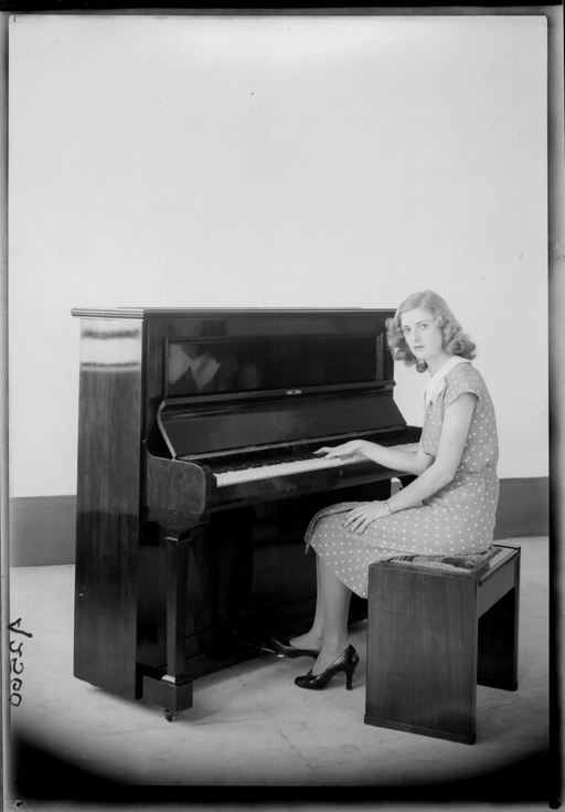 Full length portrait of a model seated at a piano for Atwaters Limited 1940