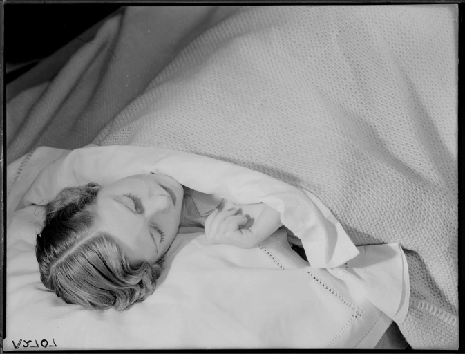 Showing a model asleep in a bed advertising bed linen and blankets for Sargood Son and Ewen 1940s