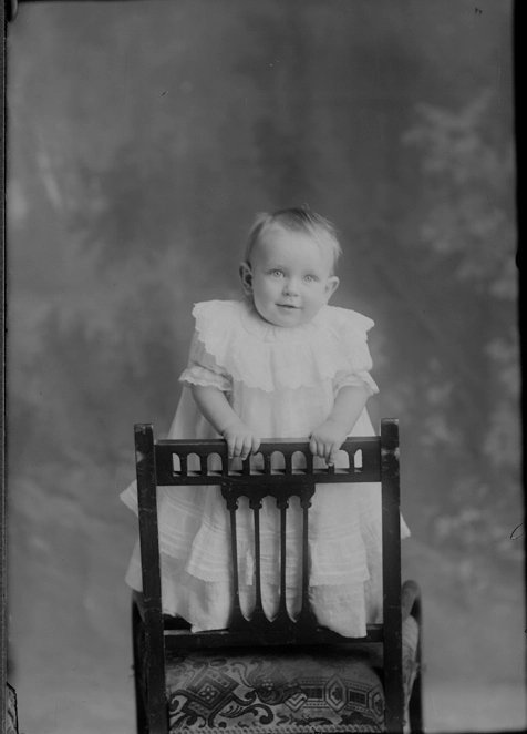 Full length portrait of baby Passmore standing on a wooden....