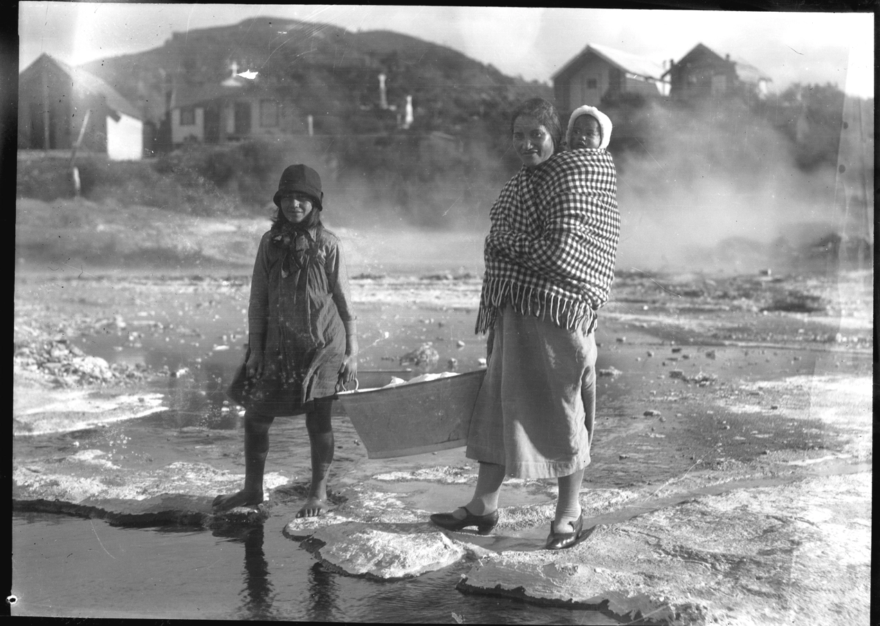 Maori woman and child carrying a tin tub