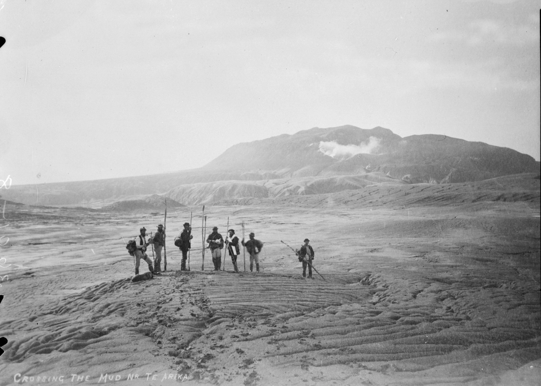 Showing a group of people crossing the mud near Te Ariki, Mount Tarawera (background) after the eruption in 1886