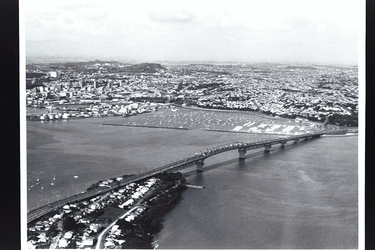 Aerial view looking south towards Auckland City from the North Shore showing Stokes Point, the Auckland Harbour Bridge, Westhaven Boat Harbour..., 1970s