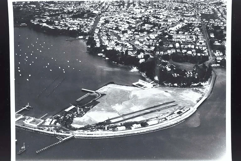 Aerial view looking south east over Westhaven Boat Harbour showing preparations for the Auckland Harbour Bridge... 1955