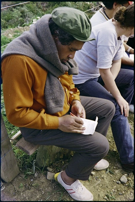 Poet Hone Tuwhare writing in his notepad during a stop on the Maori Land March