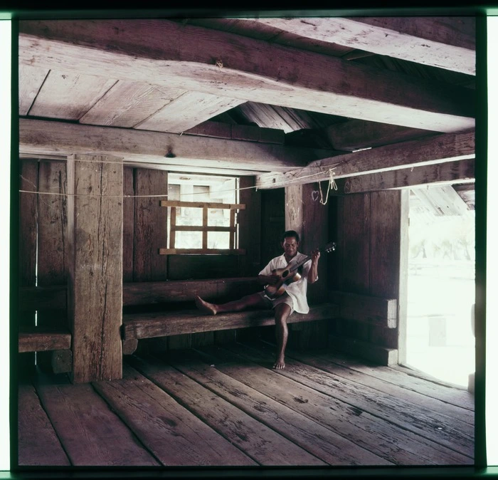 Temotu Arioka playing his guitar inside the Tin House, Palmerston Island.