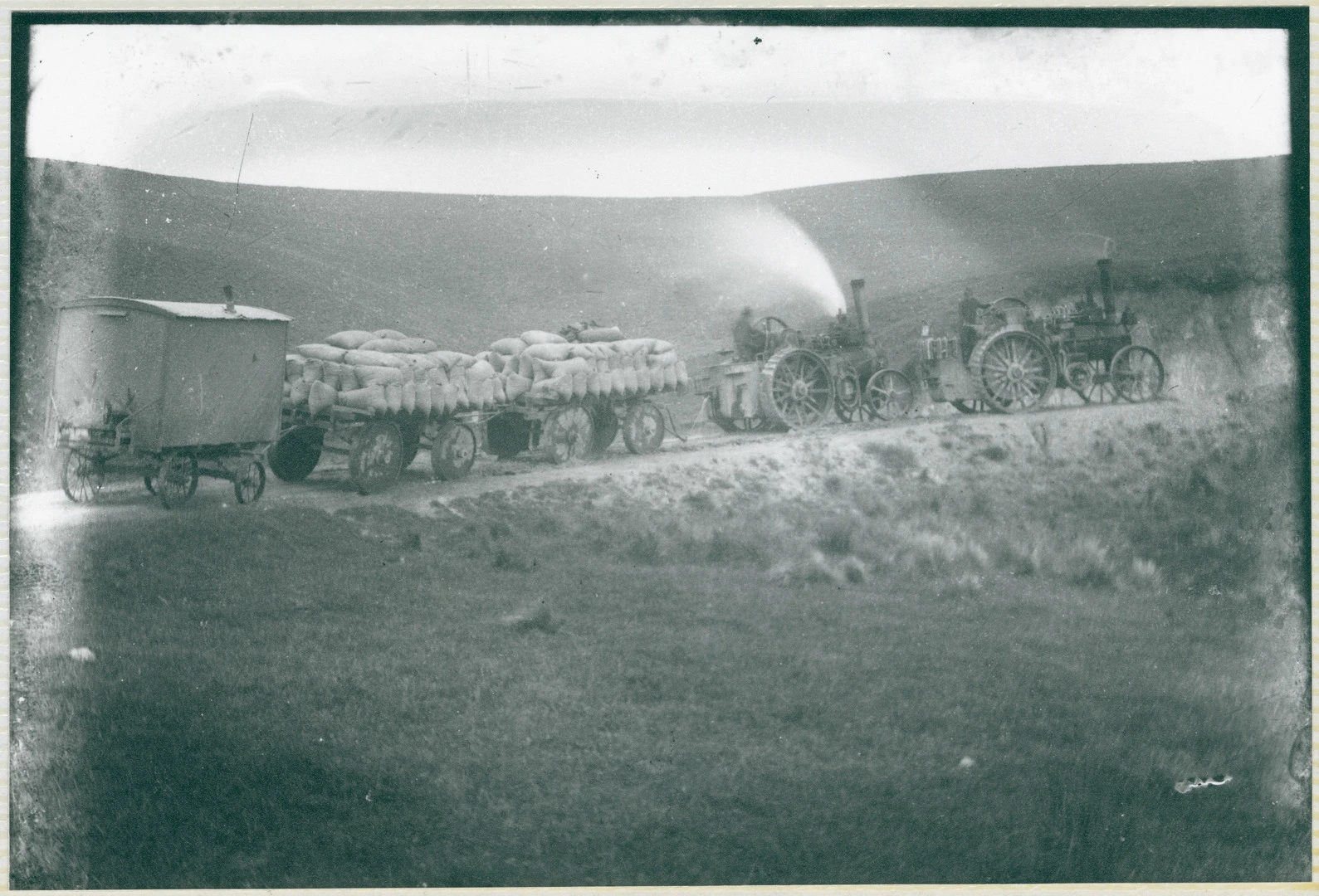 Tractors pulling wagons up a hill