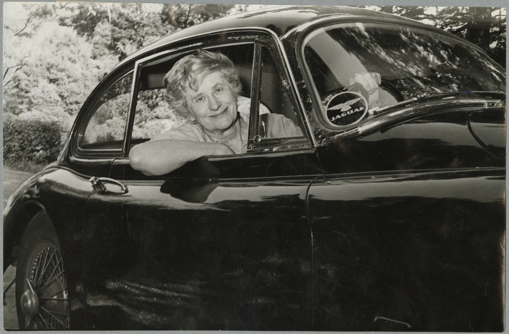 Ngaio Marsh sitting in her Jaguar XK150