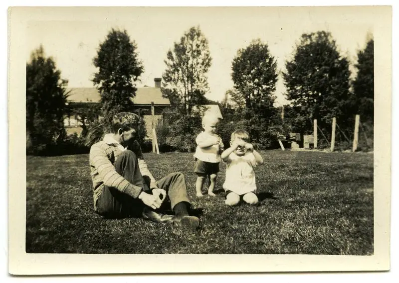 Photograph, Black and White: Colin Lovell-Smith sitting on a lawn with his sons Richard and John