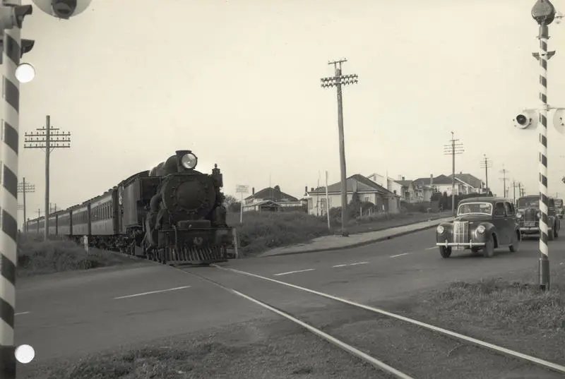 Steam locomotive WAB 769 and passenger train at level crossing, 1954