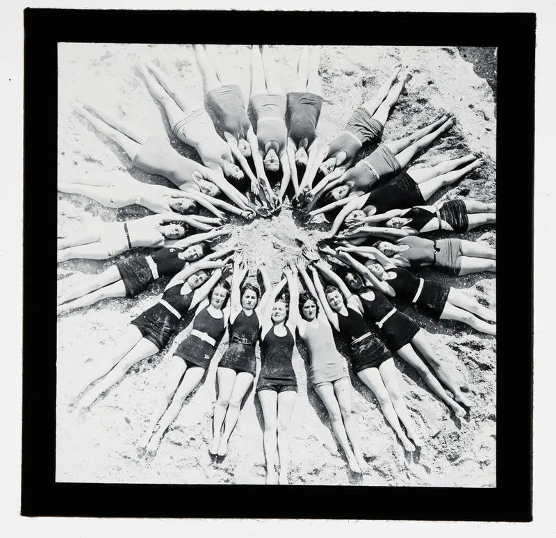 Unidentified group on beach lying in formation on sand