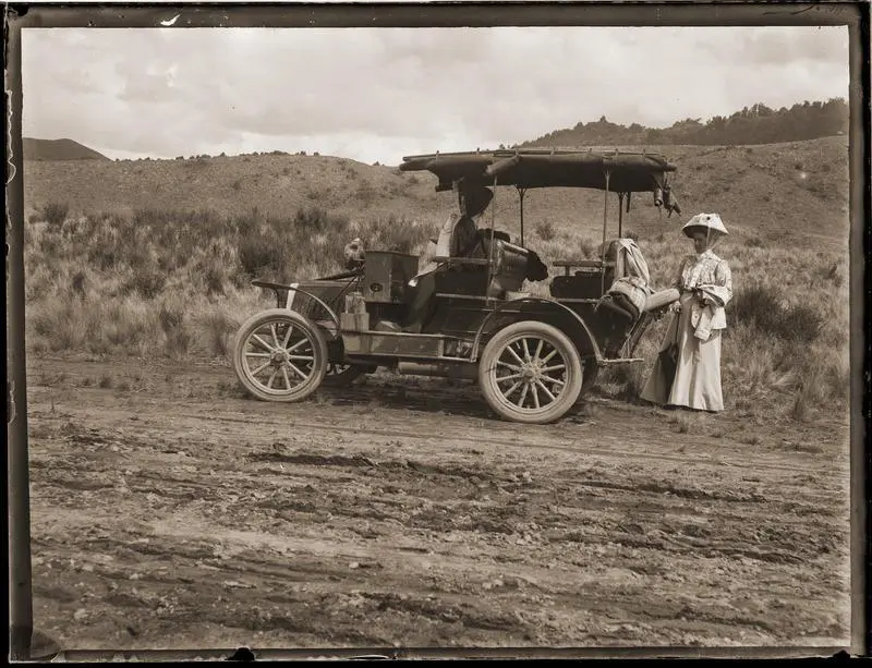 Two women and car beside road.