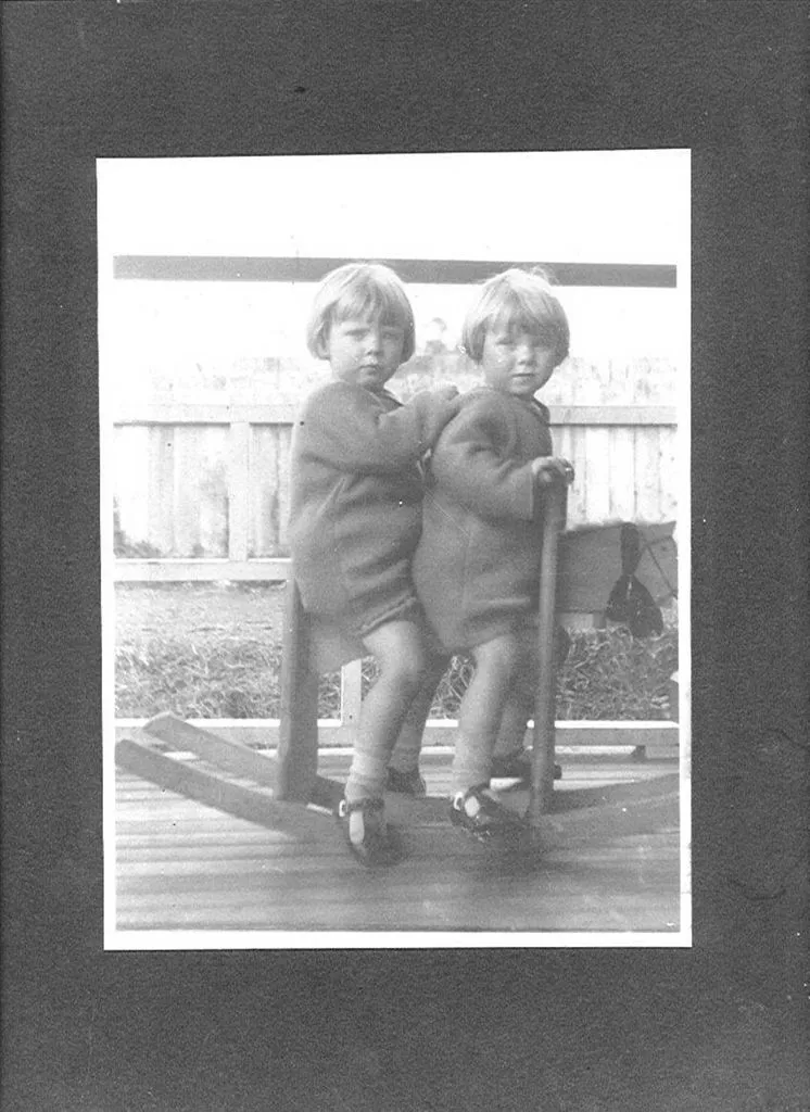 Two unidentified girls on a wooden rocking horse