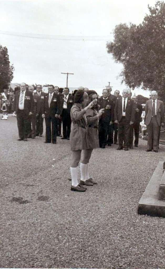 Two girls "Brownies" saluting after laying wreath, Anzac Day mid 1970's