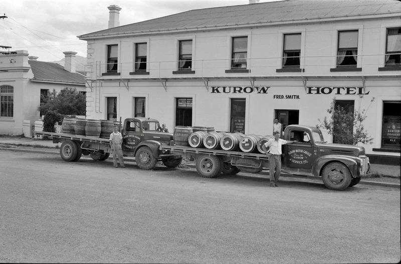 Building. Hotel. Kurow Hotel, Fred Smith Proprietor, With two Trucks Loaded Outside. Empties or Full? The Trade in Barrels Goes on. Kurow, Otago, New Zealand.