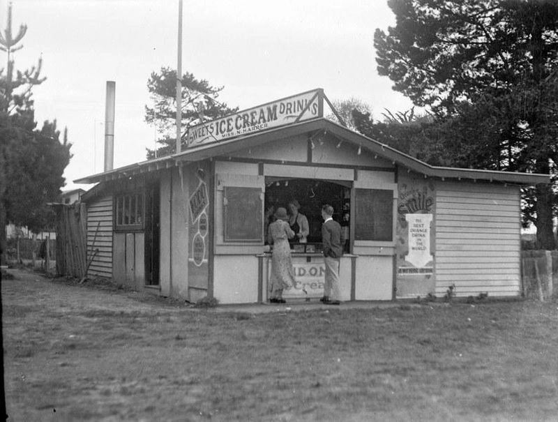 Waikuku Beach. Shop. Miss N. Harper Serving Customers Ice Cream at the Sweet Shop, Waikuku Beach. Canterbury, New Zealand.