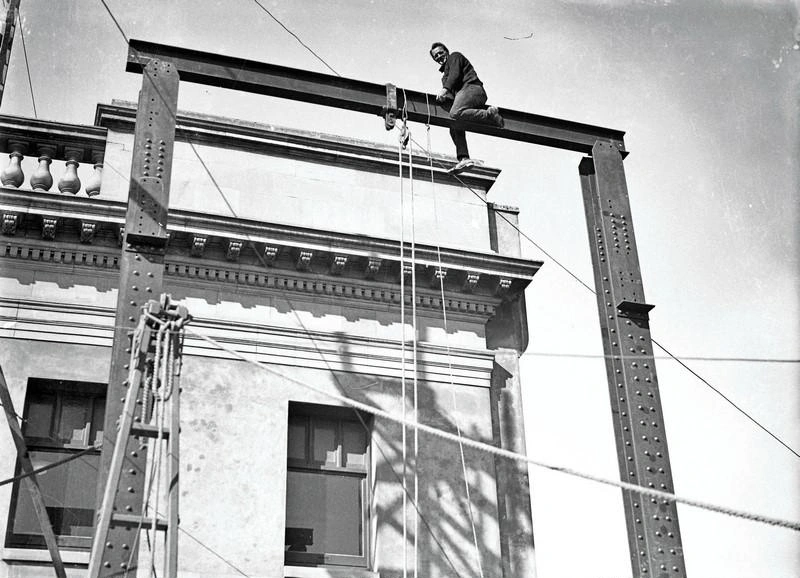 Central City. Building Construction, Erecting Steel Girders, Man on Top. In Front of the Old Government Buildings, Cathedral Square, Christchurch, Canterbury, New Zealand.