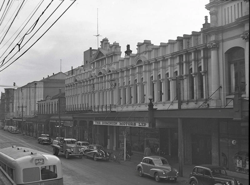 Central City. Streetscape from the State Movie Theatre at the left on the corner of Colombo Street to the Dominion Motors Ltd ( Morris Distributors ) Building on the Right. Of Interest is the Streamlined Car in the Centre, an Austin A90 Atlantic ( Produced 1949-1952. The Bus is Destined for the "Sq" Meaning Cathedral Square. Gloucester Street, Christchurch, Canterbury, New Zealand.