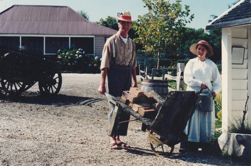 Keith Morton in costume pushing a cart laden with bricks and Penny Hill holding a watering can on a Live Day at HHV.