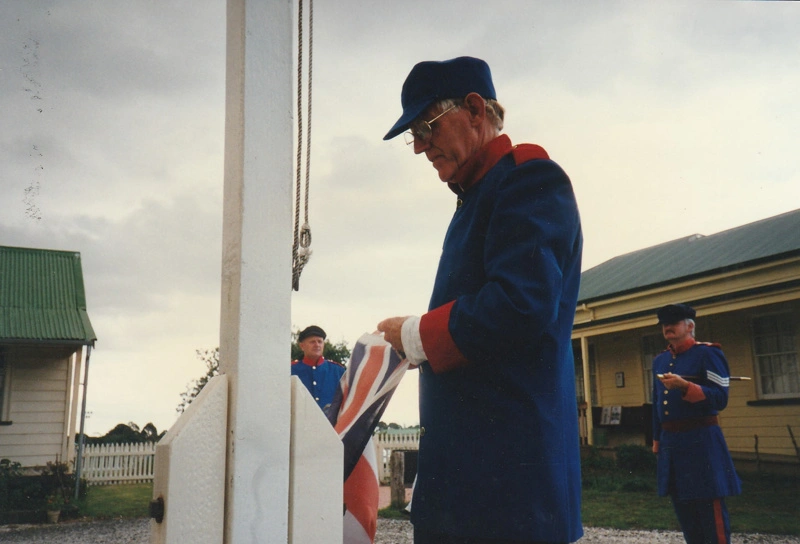 Alan la Roche in Fencible uniform at the flagpole in Howick Historical Village.