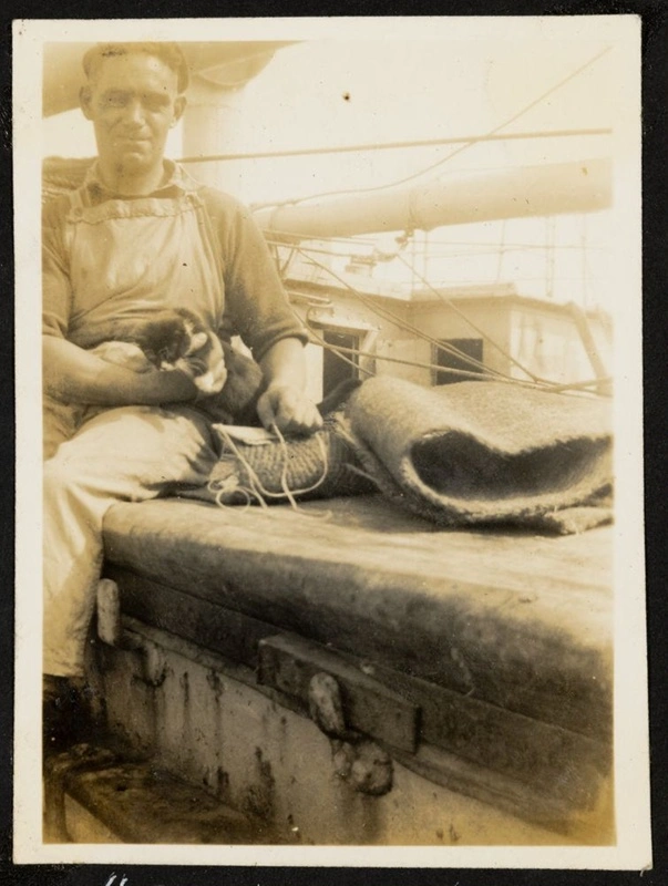 Unidentified man, labelled as the Bosun, holds a cat on deck of unidentified ship.