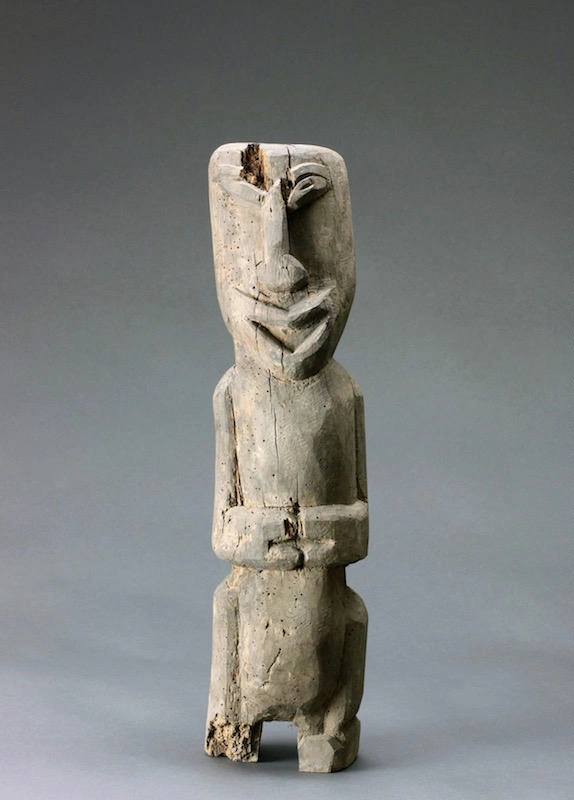 Carved wooden totem with short legs, crossed arms and a smile