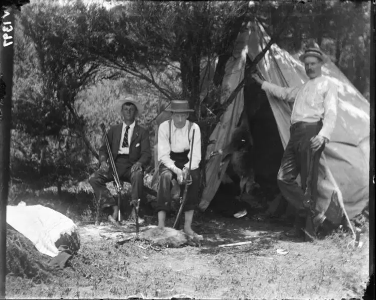 Three unidentified men outside a tent