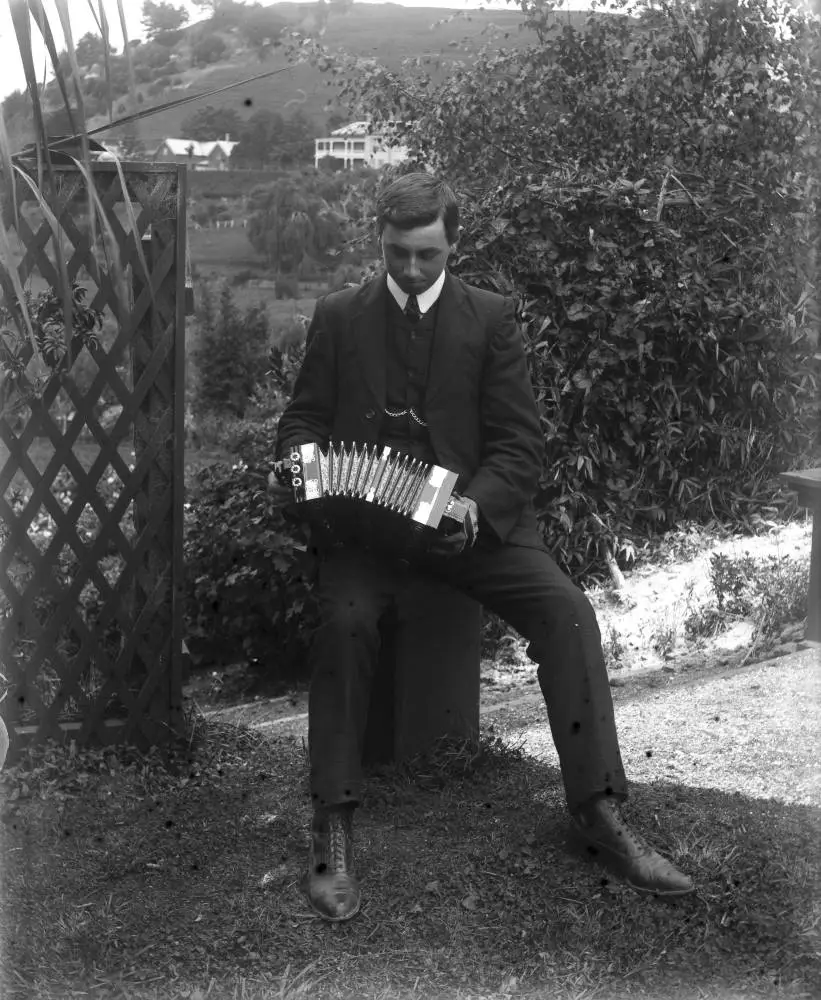 Man playing an accordion, Arney Road, Remuera, 1909