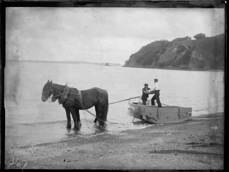 Two men loading a sledge on a beach