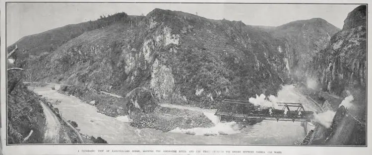 A PANORAMIC VIEW OF KARANGAHAKE GORGE, SHOWING THE OHINEMURI RIVER, AND THE TRAIN CROSSING THE BRIDGE BETWEEN PAEROA AND WAIHI