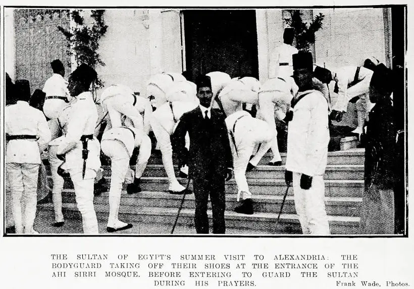 The Sultan of Egypt's summer visit to Alexandria: the bodyguard taking off their shoes at the entrance of the Ahi Sirri Mosque, before entering to guard the Sultan during his prayers