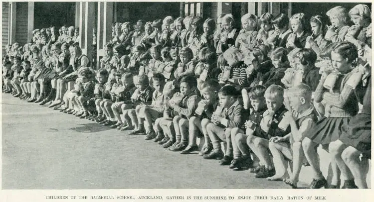 Children of the Balmoral School, Auckland, gather in the sunshine to enjoy their daily ration of milk