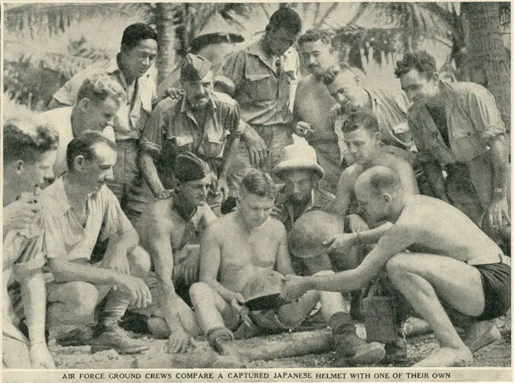Air force ground crews compare a captured Japanese helmet with one of their own