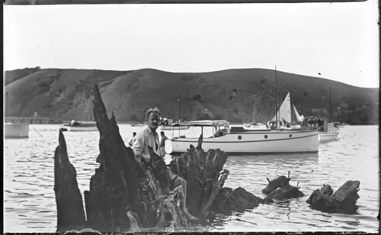 Man sitting on partly submerged hulk M A Doran, 1930s