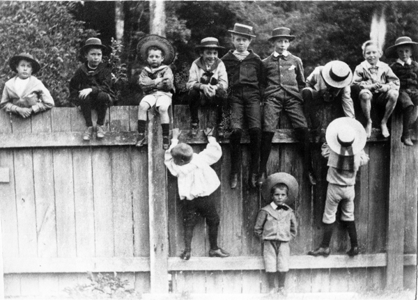 Photograph: Twelve children sitting on a fence at "Te Rakaunui", Greytown