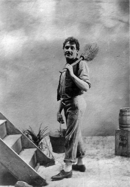 A theatrical scene of a man with a bucket and a broom