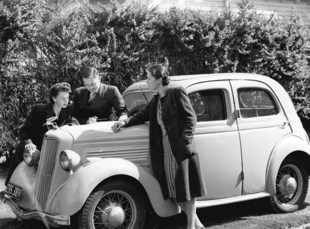 Man and girls by car consulting a road map