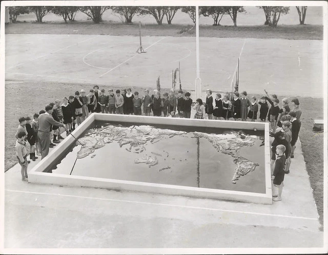 Mr. N. R. Jones takes a class in Geography at the concrete relief map of the world in the grounds of the May Road Primary School, Mt. Roskill, Auckland.