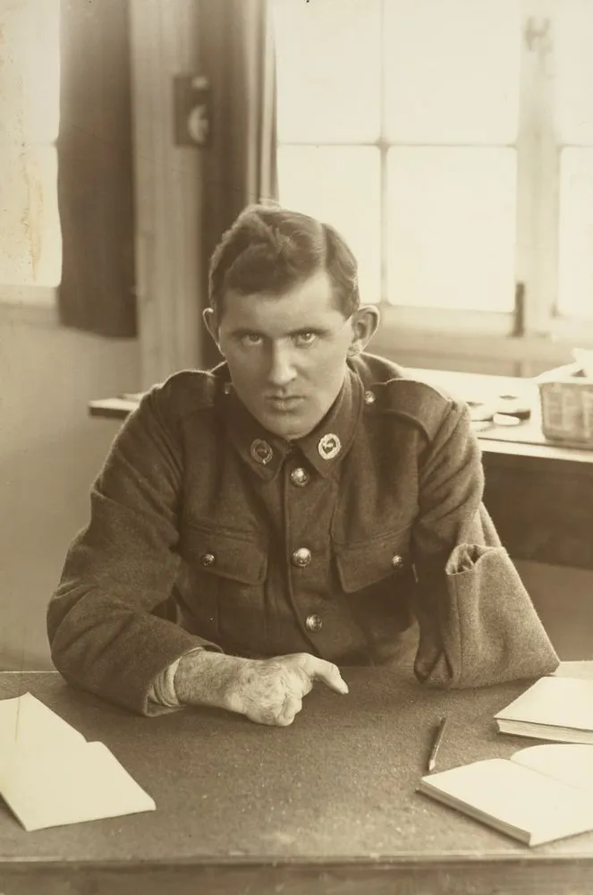 WWI soldier Allan McMillan sitting at a desk at Oatlands Park, Surrey, England