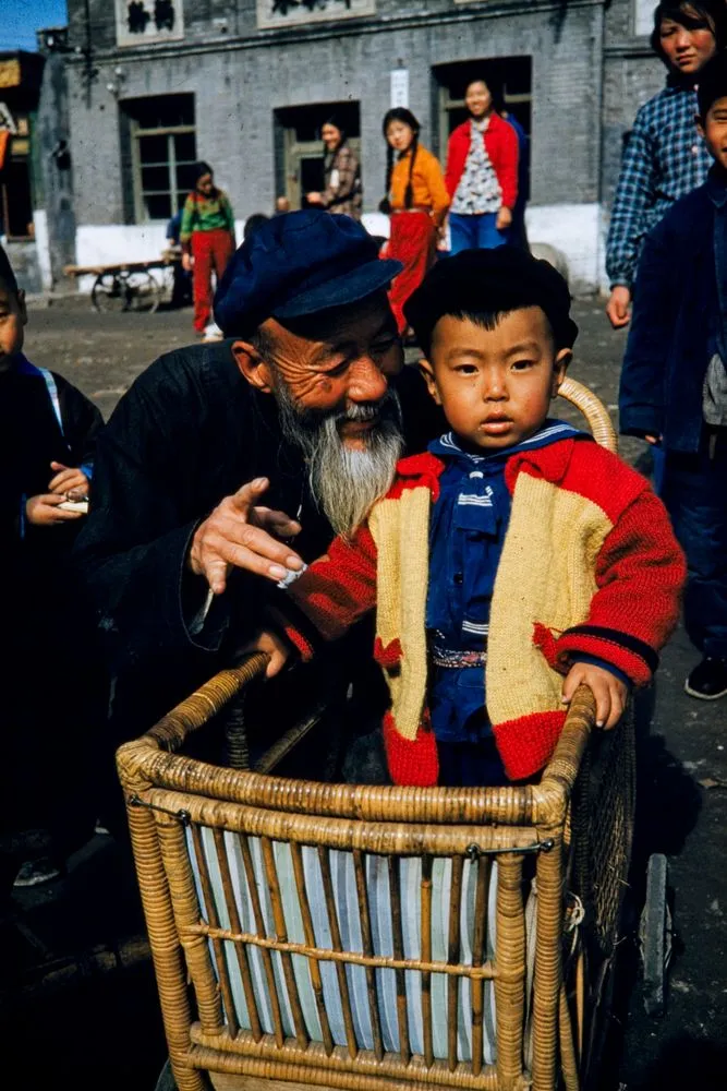 Child in rattan pram with grandfather